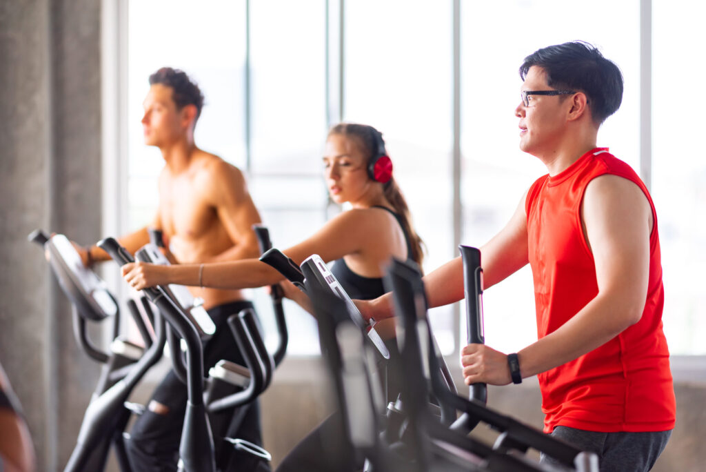 A group of people working out on elliptical machines in a gym, focusing on cardio exercise. The bright fitness center setting highlights endurance training and heart health benefits.