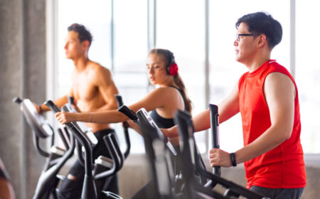 A group of people working out on elliptical machines in a gym, focusing on cardio exercise. The bright fitness center setting highlights endurance training and heart health benefits.